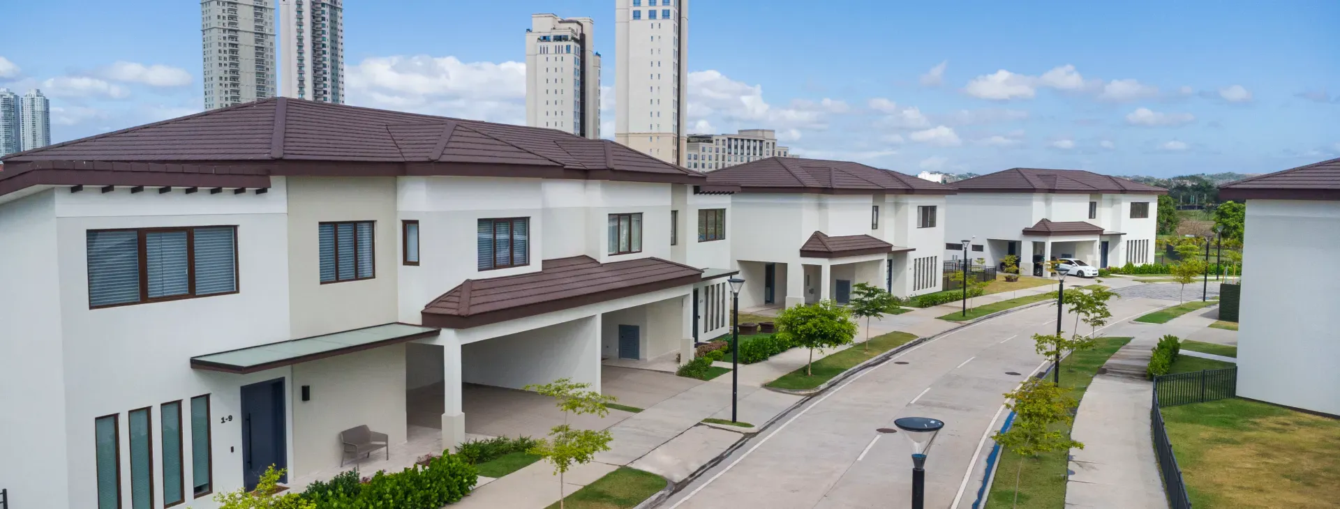Calle interna de The Woods en Santa María, con casas dúplex de dos plantas y torres residenciales al fondo